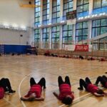grupa uczestników ćwiczy na hali sportowej